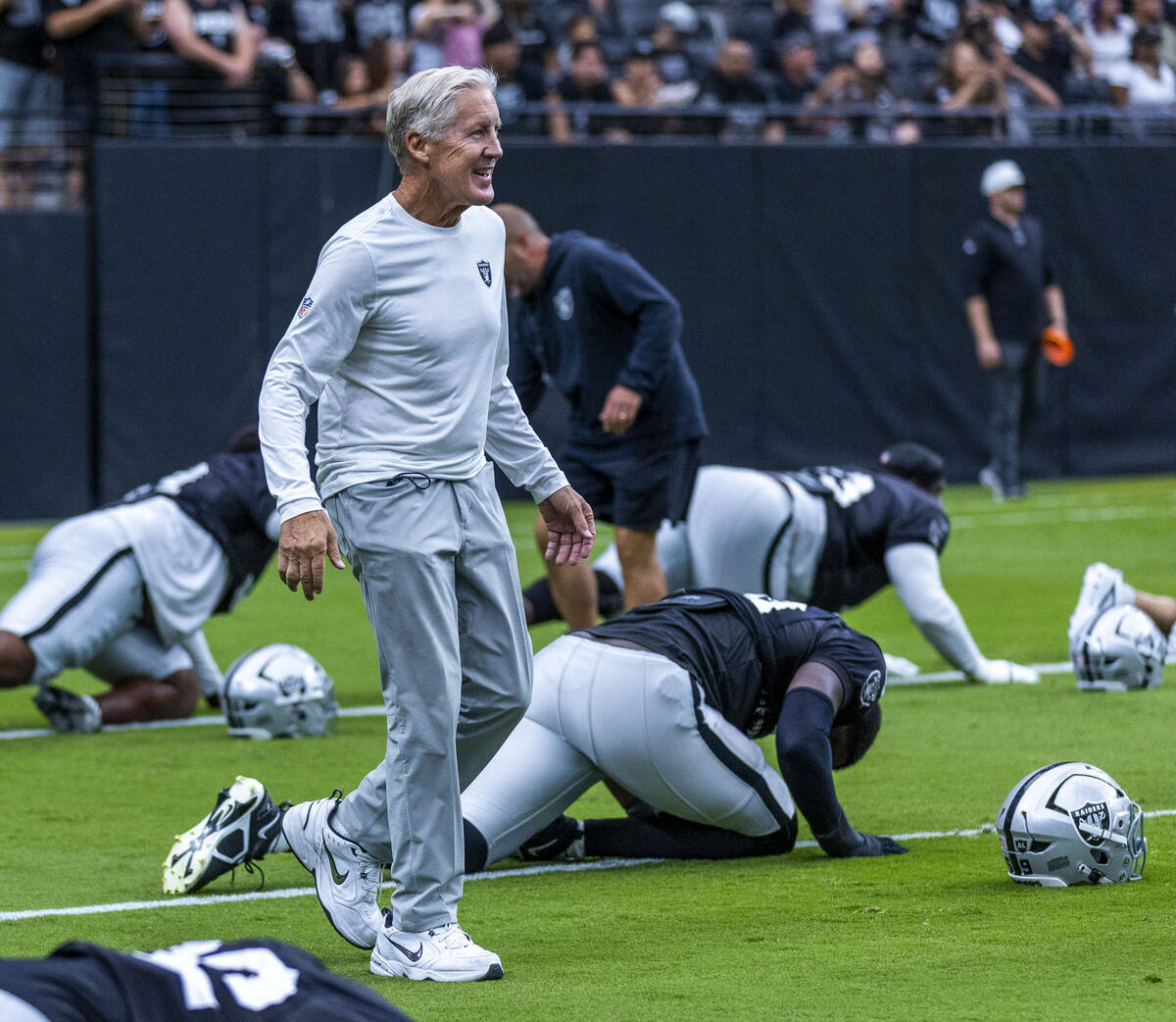 Raiders head coach Pete Carroll greets his players as they stretch during the first half of a R ...