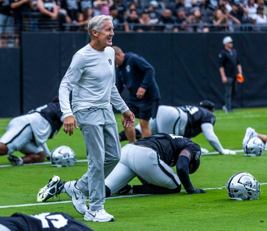 Raiders head coach Pete Carroll greets his players as they stretch during the first half of a R ...