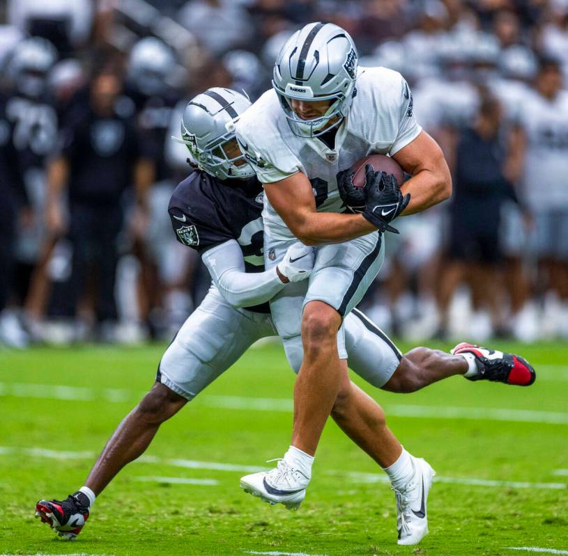 Raiders tight end Michael Mayer (87) works to break a tackle by safety Thomas Harper (34) durin ...
