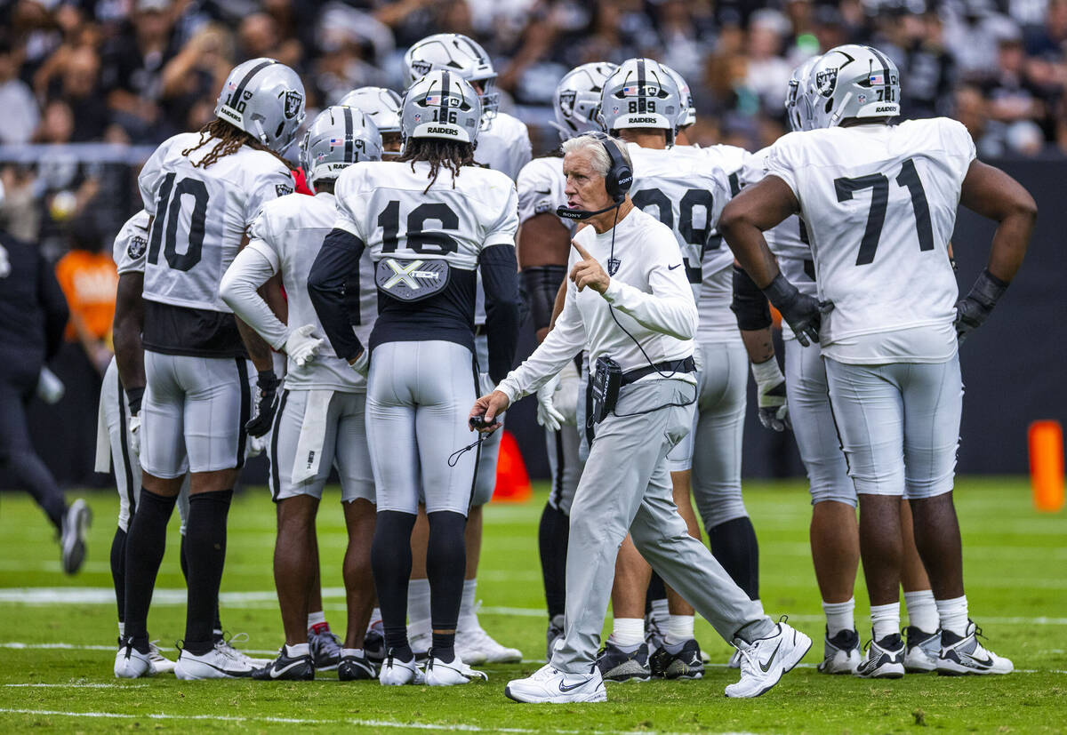 Raiders head coach Pete Carroll makes a call before a huddle during the first half of a Raiders ...