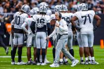 Raiders head coach Pete Carroll makes a call before a huddle during the first half of a Raiders ...