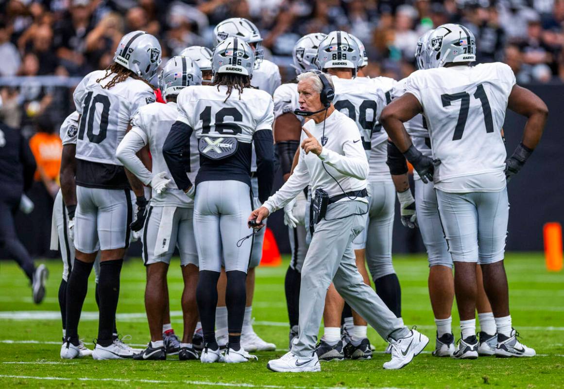 Raiders head coach Pete Carroll makes a call before a huddle during the first half of a Raiders ...