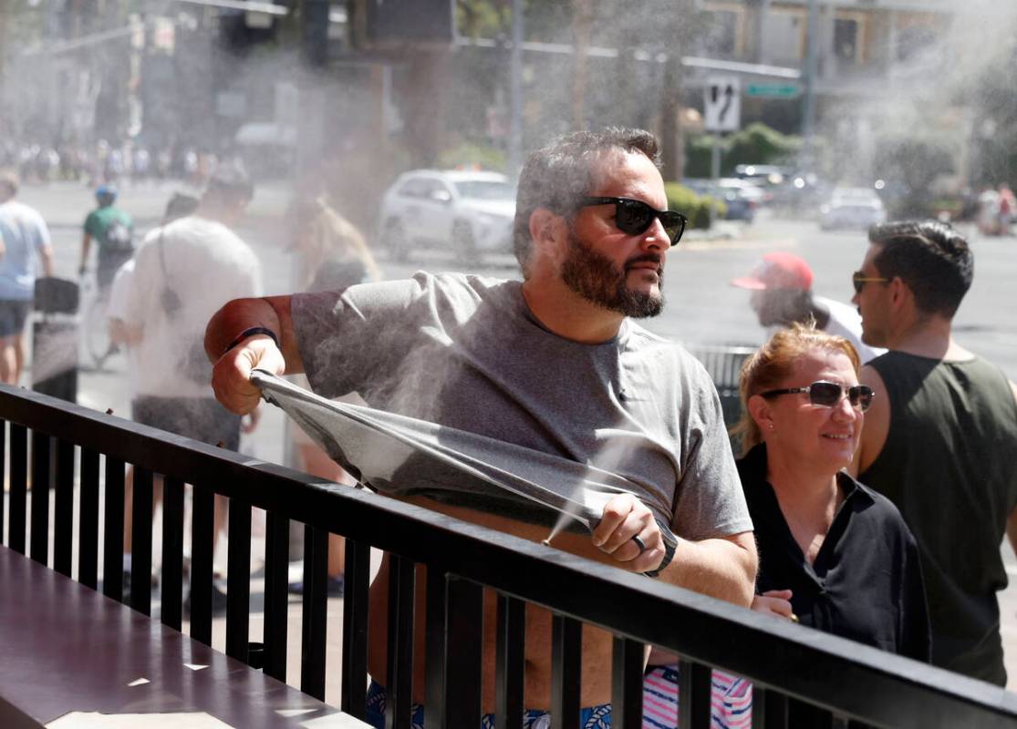 As the temperature climbs towards triple digits, a pedestrian cools off with water misters alon ...