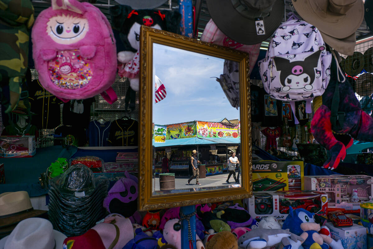 People are reflected in a mirror at a booth while exploring the Broadacres Marketplace swap mee ...