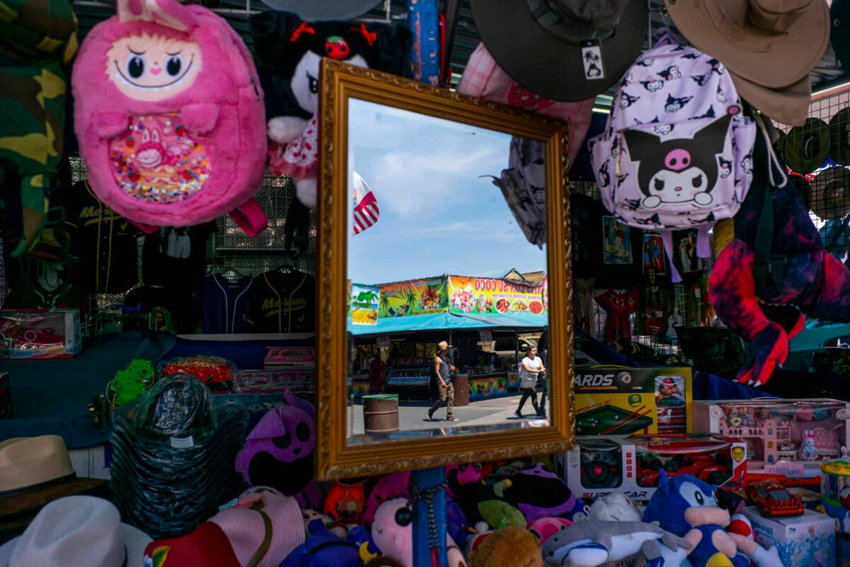 People are reflected in a mirror at a booth while exploring the Broadacres Marketplace swap mee ...