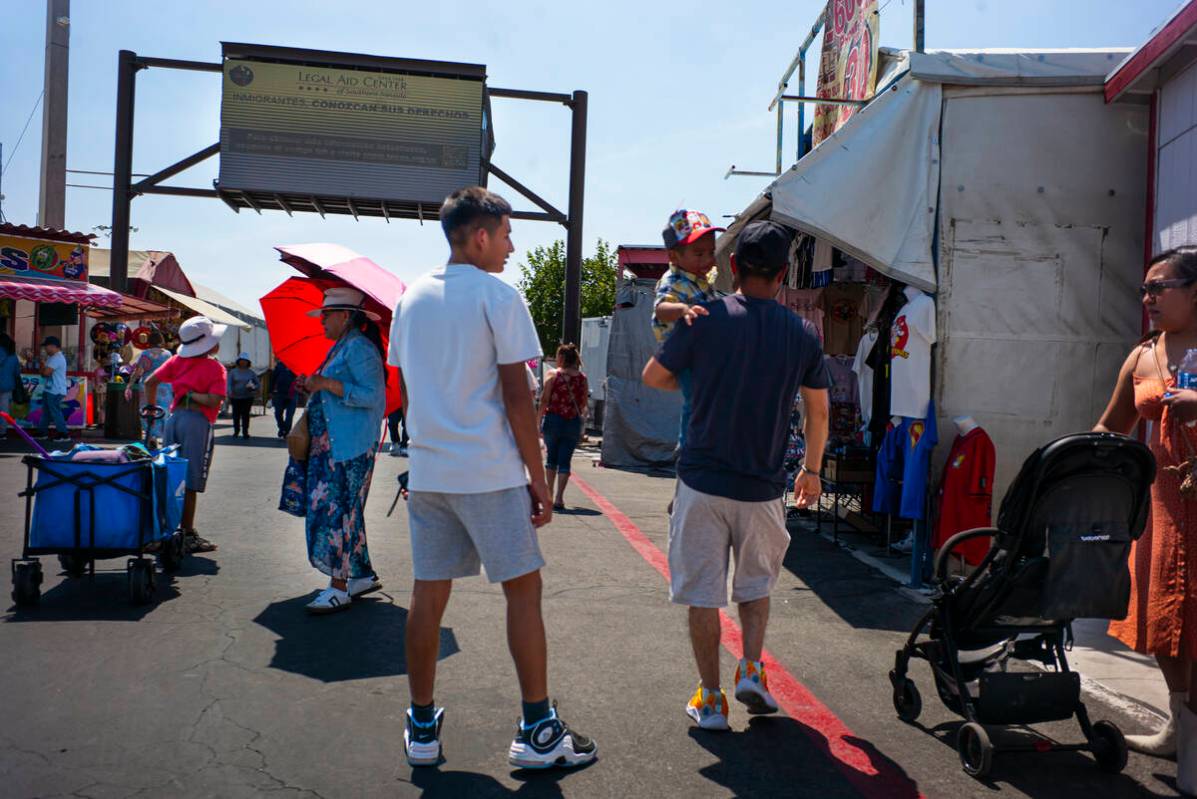 People explore the Broadacres Marketplace swap meet as a digital billboard from the Legal Aid C ...