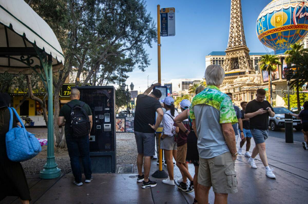 People look at different routes as others wait at a Regional Transportation Commission bus stop ...