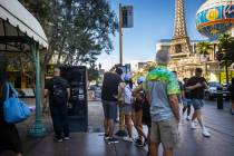 People look at different routes as others wait at a Regional Transportation Commission bus stop ...