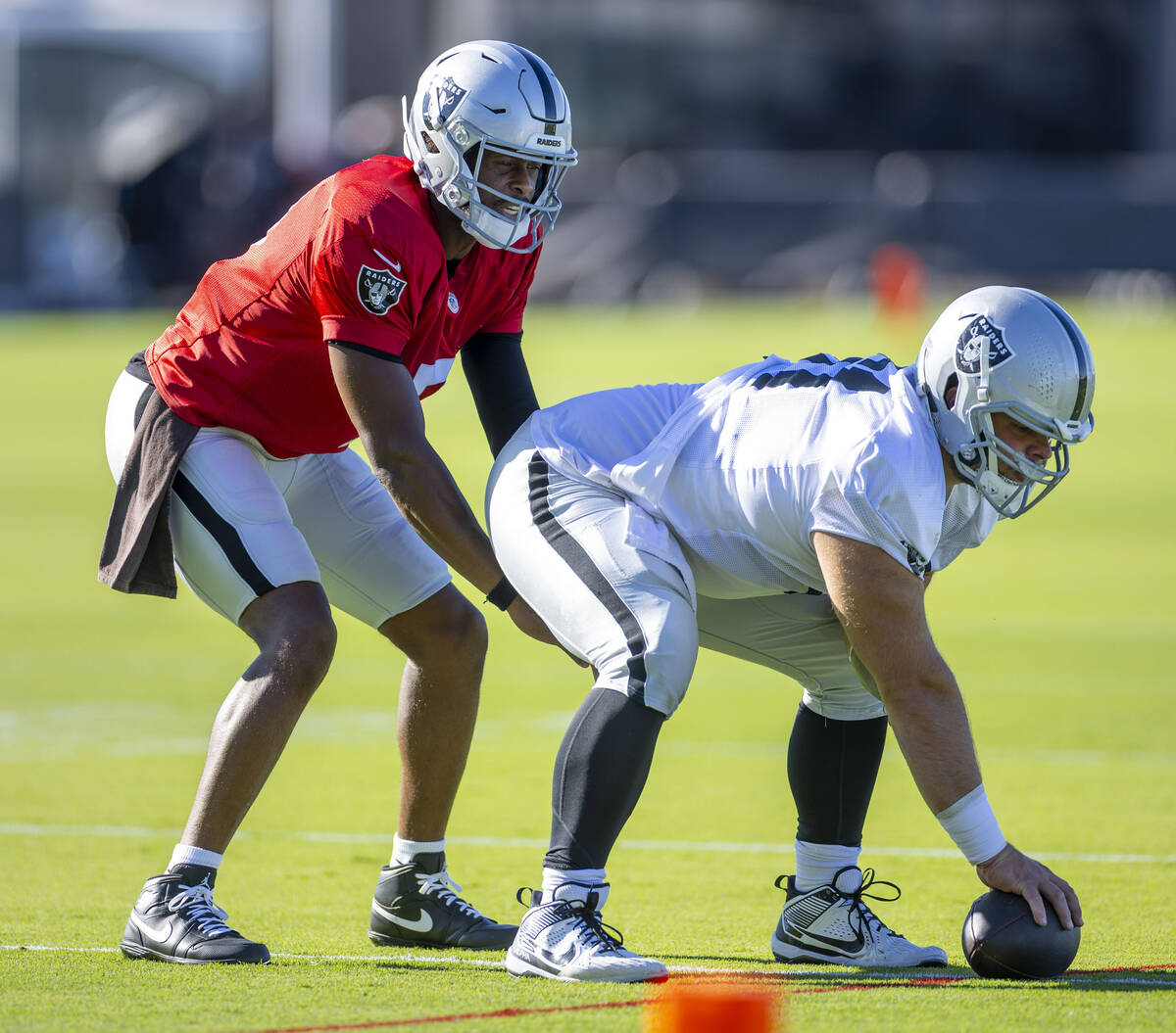 Raiders quarterback Geno Smith (7) takes a snap from guard Jordan Meredith (61) during training ...