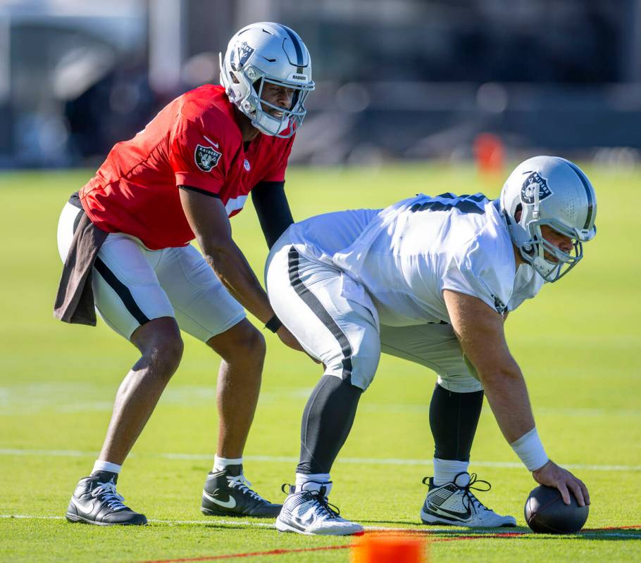 Raiders quarterback Geno Smith (7) takes a snap from guard Jordan Meredith (61) during training ...