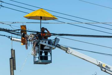 A lineman works beneath an umbrella along West Owens Avenue Friday, May 30, 2025, in Las Vegas. ...