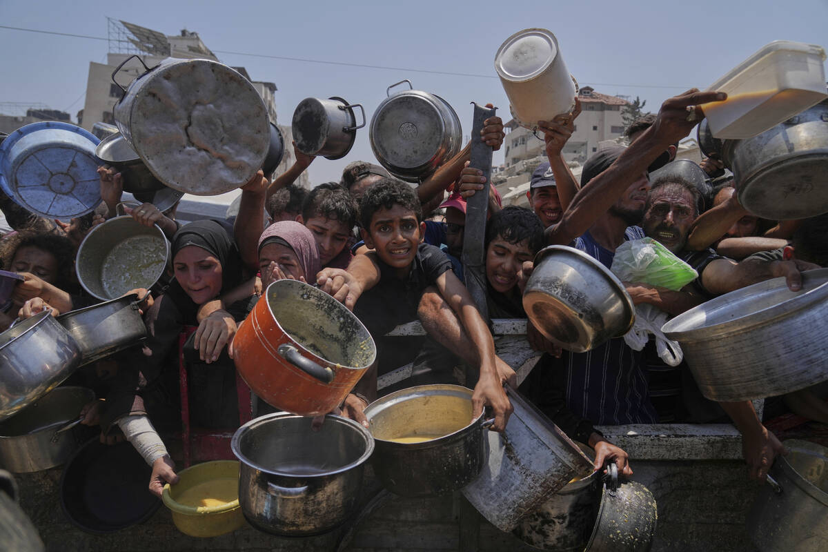 Palestinians struggle to get donated food at a community kitchen, in Gaza City, northern Gaza S ...