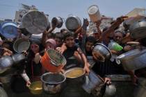 Palestinians struggle to get donated food at a community kitchen, in Gaza City, northern Gaza S ...