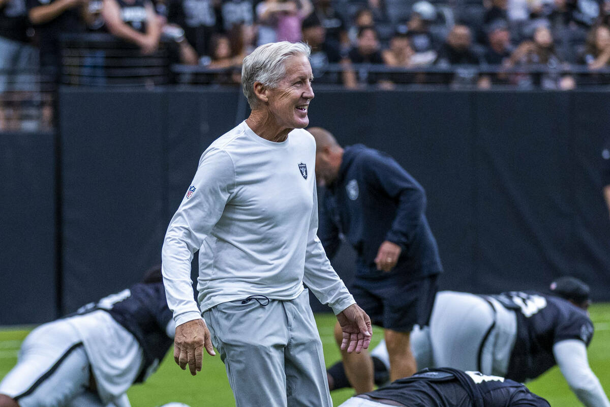 Raiders head coach Pete Carroll greets his players as they stretch during the first half of a R ...