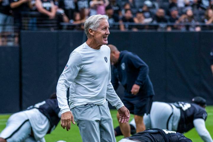 Raiders head coach Pete Carroll greets his players as they stretch during the first half of a R ...