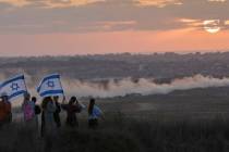 Israeli right-wing activists watch the northern Gaza Strip during a rally calling for the re-es ...