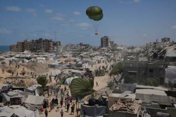 Palestinians rush to collect humanitarian aid airdropped by parachutes into Gaza City, northern ...