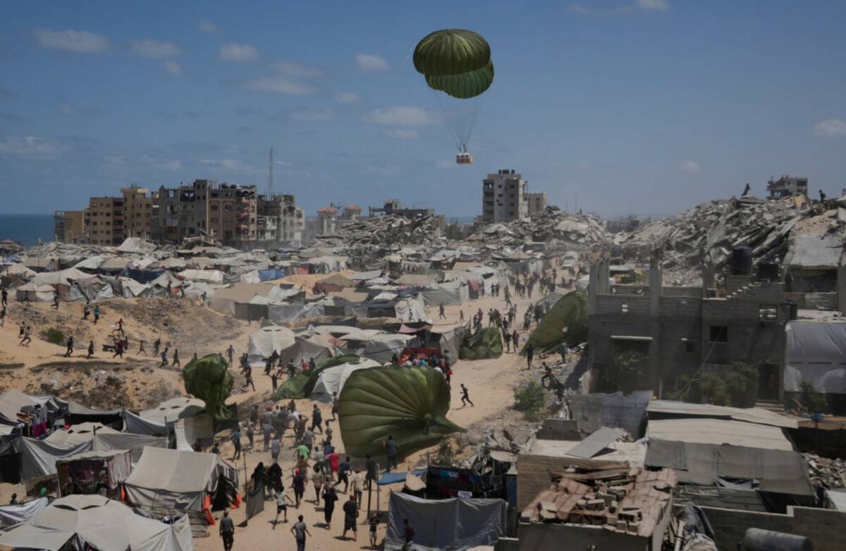Palestinians rush to collect humanitarian aid airdropped by parachutes into Gaza City, northern ...