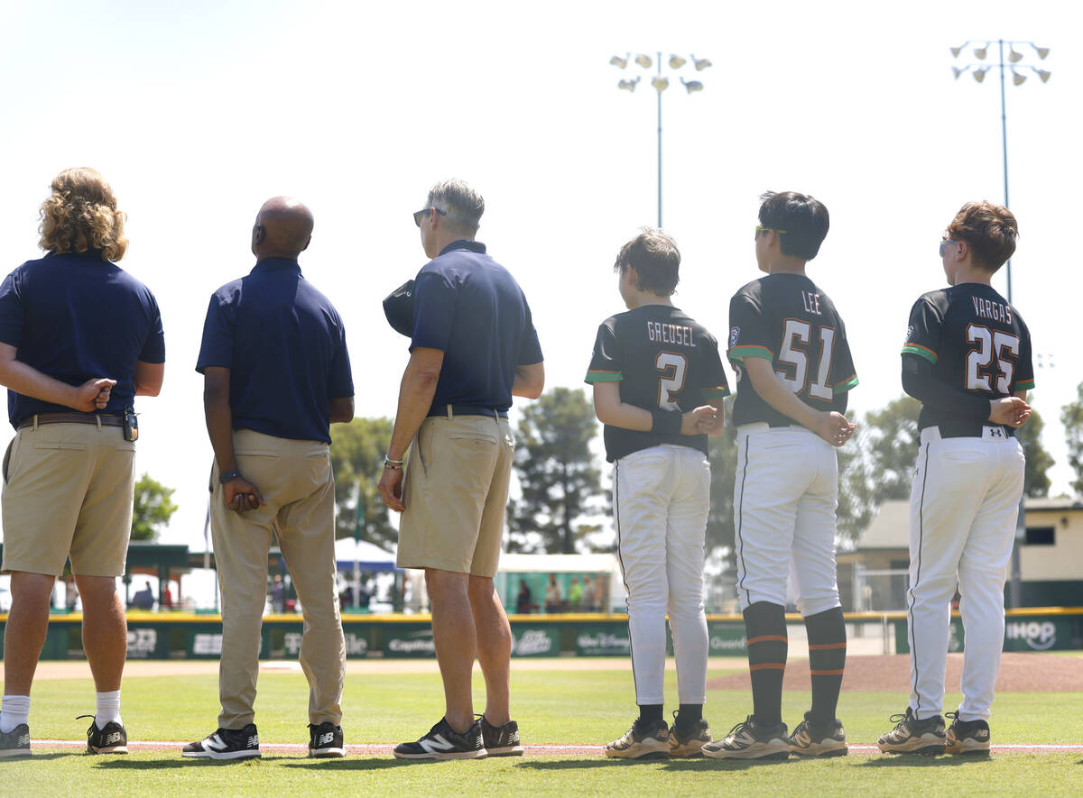 Nevada Little League baseball players and coaches line up during the National Anthem before the ...