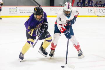 Players race pursue a puck during a Golden Knights high school hockey league game at America Fi ...