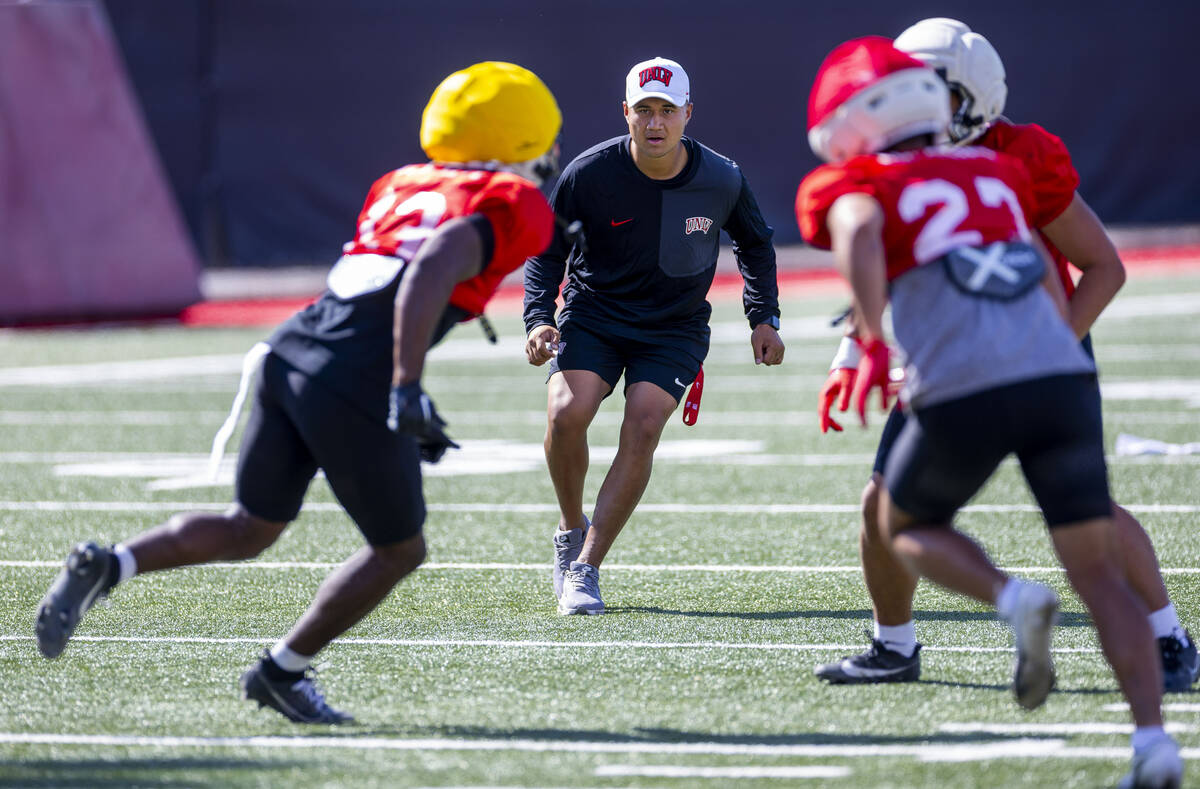 UNLV linebacker's coach Bam Amina runs with linebacker Darien "Bleu" Stewart (13) and ...