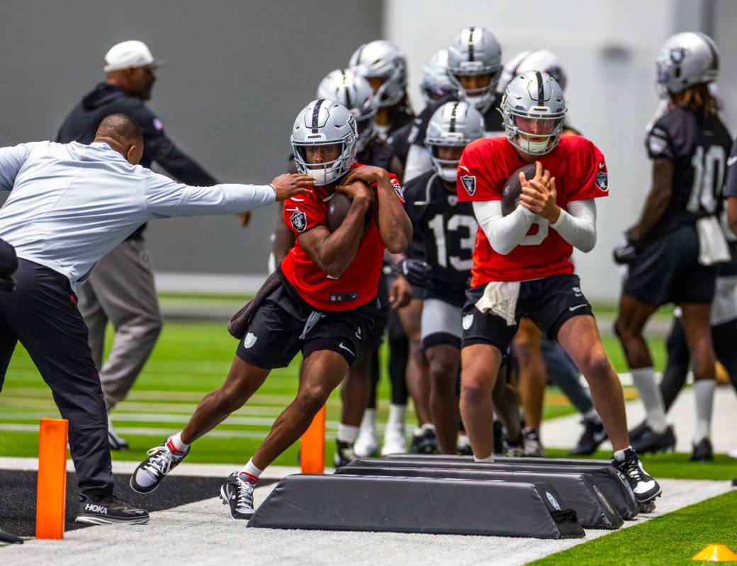 Raiders quarterbacks Geno Smith (7) and Cam Miller (5) lead a drill during training camp in the ...