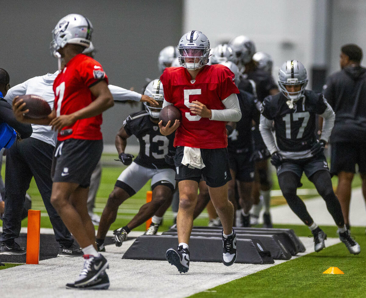 Raiders quarterbacks Geno Smith (7) and Cam Miller (5) lead a drill during training camp in the ...