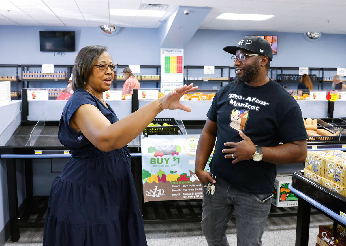 Dewayne McCoy, owner of The After Market, right, listens as North Las Vegas mayoral candidate D ...