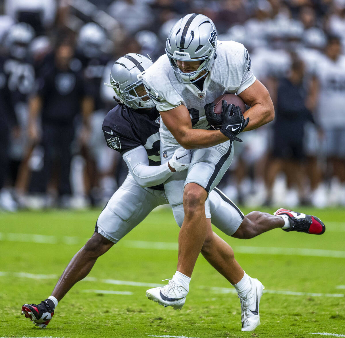 Raiders tight end Michael Mayer (87) works to break a tackle by safety Thomas Harper (34) durin ...