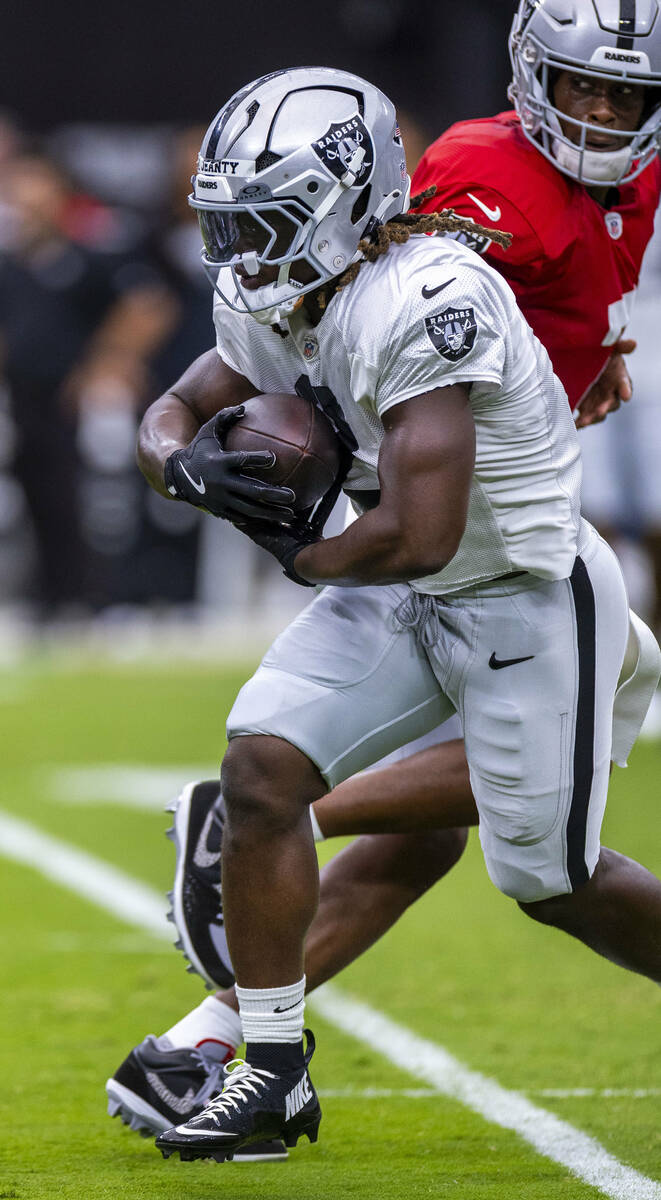 Raiders running back Ashton Jeanty (2) takes a hand off from quarterback Geno Smith (7) during ...