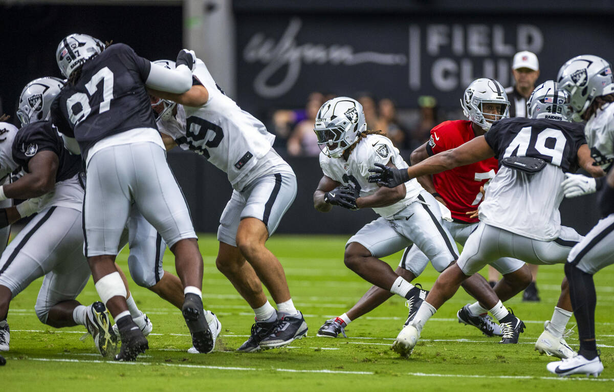 Raiders running back Ashton Jeanty (2) looks for an opening on the line with a block from tight ...