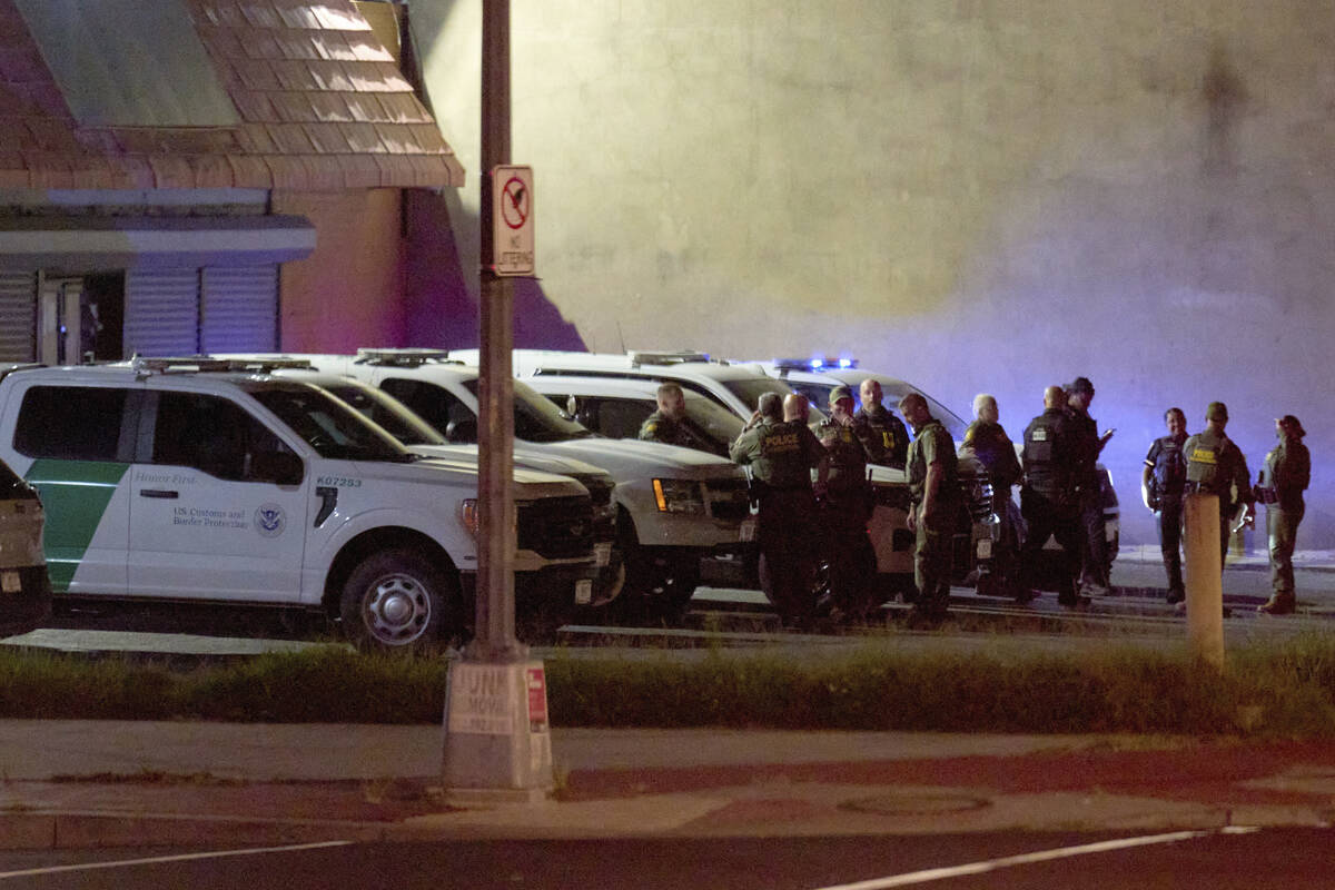 Agents with U.S. Customs and Border Protection as well as Metropolitan Police wait in a parking ...