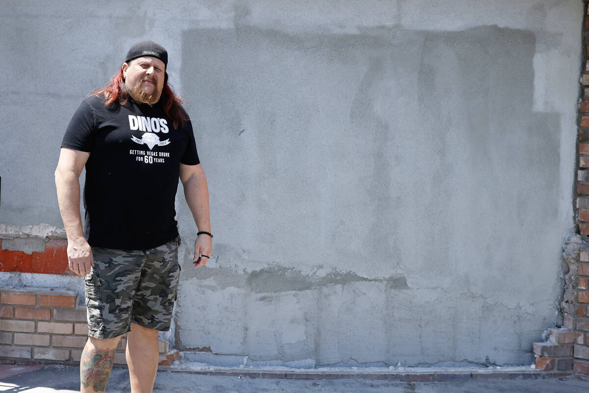 Erik Rensch, a bartender at Dino’s Lounge, poses for a photo in front of a repaired exte ...