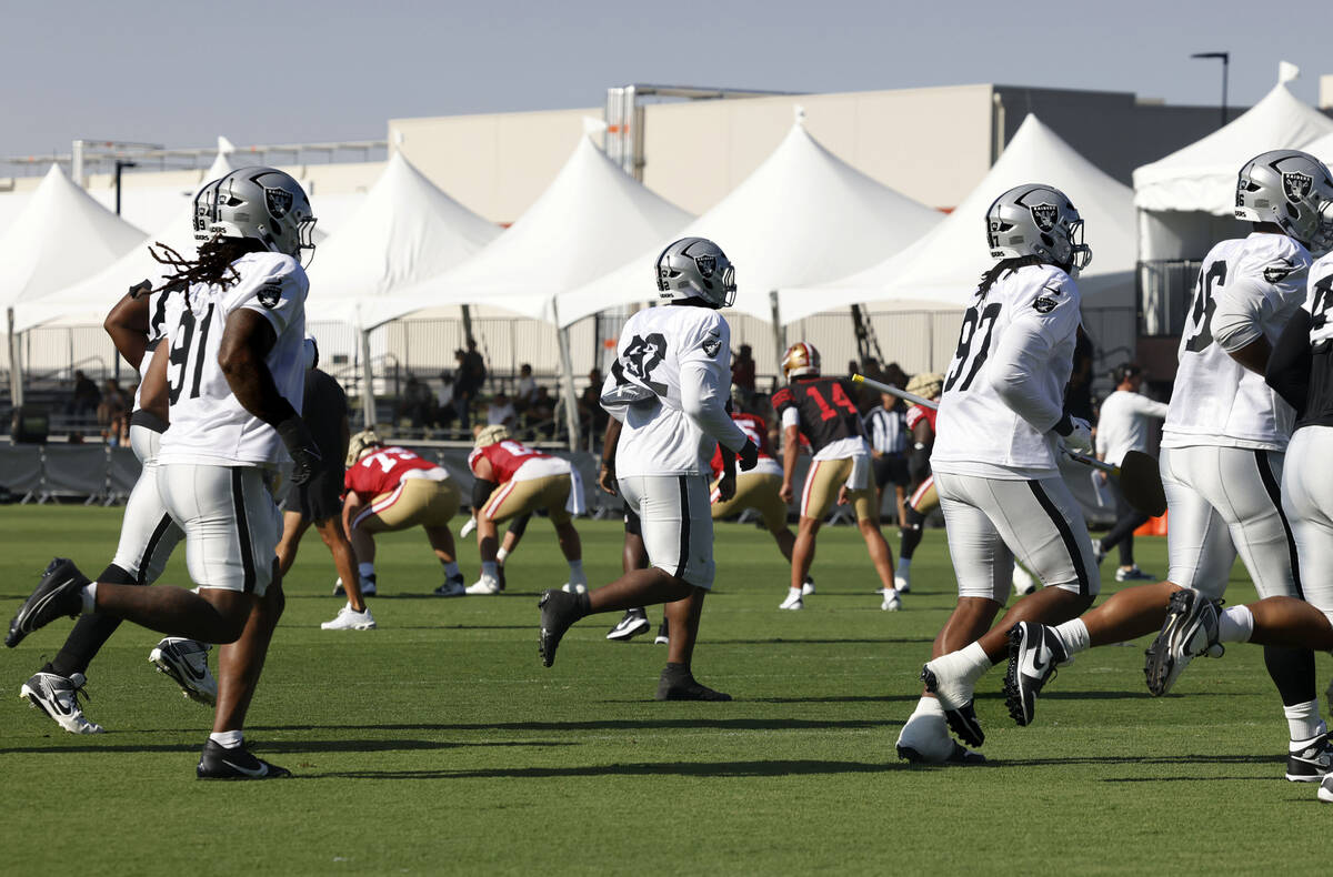 Raiders players run past San Francisco 49ers players, center, as they take the field during a j ...