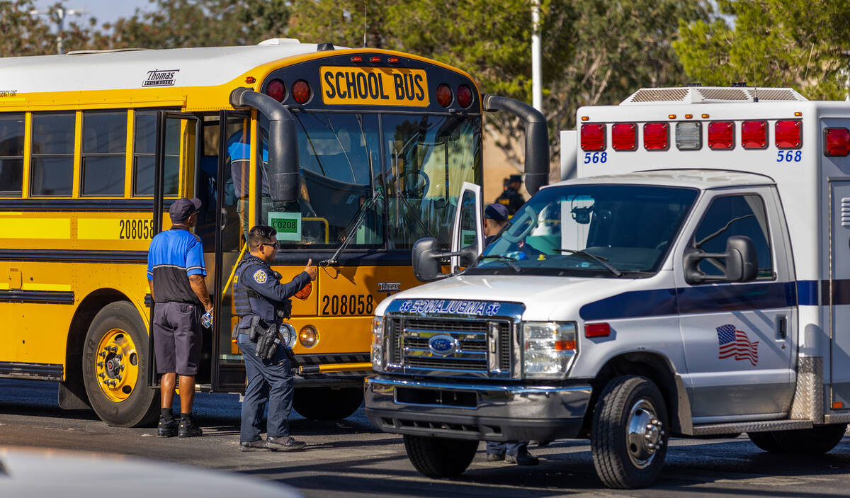 A Clark County School District officer signals others beside a damaged school bus while emergen ...