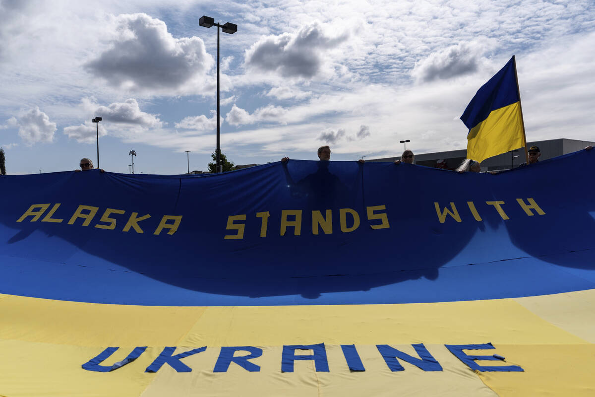 People hold a large Ukrainian flag during a rally in Anchorage, Alaska, Thursday, Aug. 14, 2025 ...