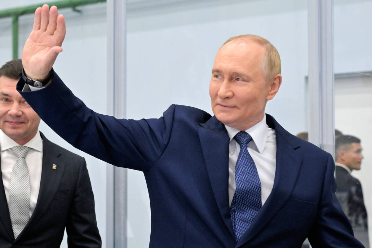 Russian Prime Minister Vladimir Putin waves while visiting the Omega Sea plant in Magadan, abou ...