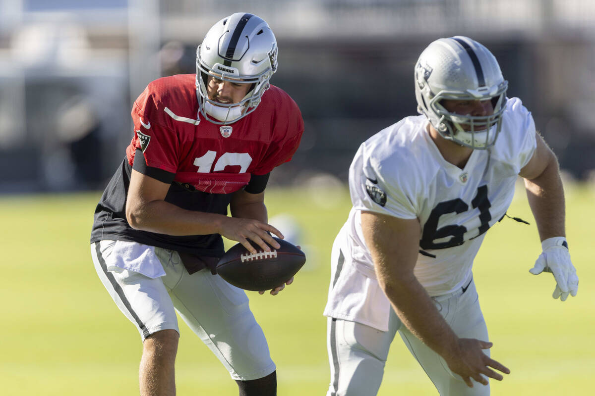 Raiders quarterback Aidan O'Connell (12) takes a snap from guard Jordan Meredith (61) during th ...