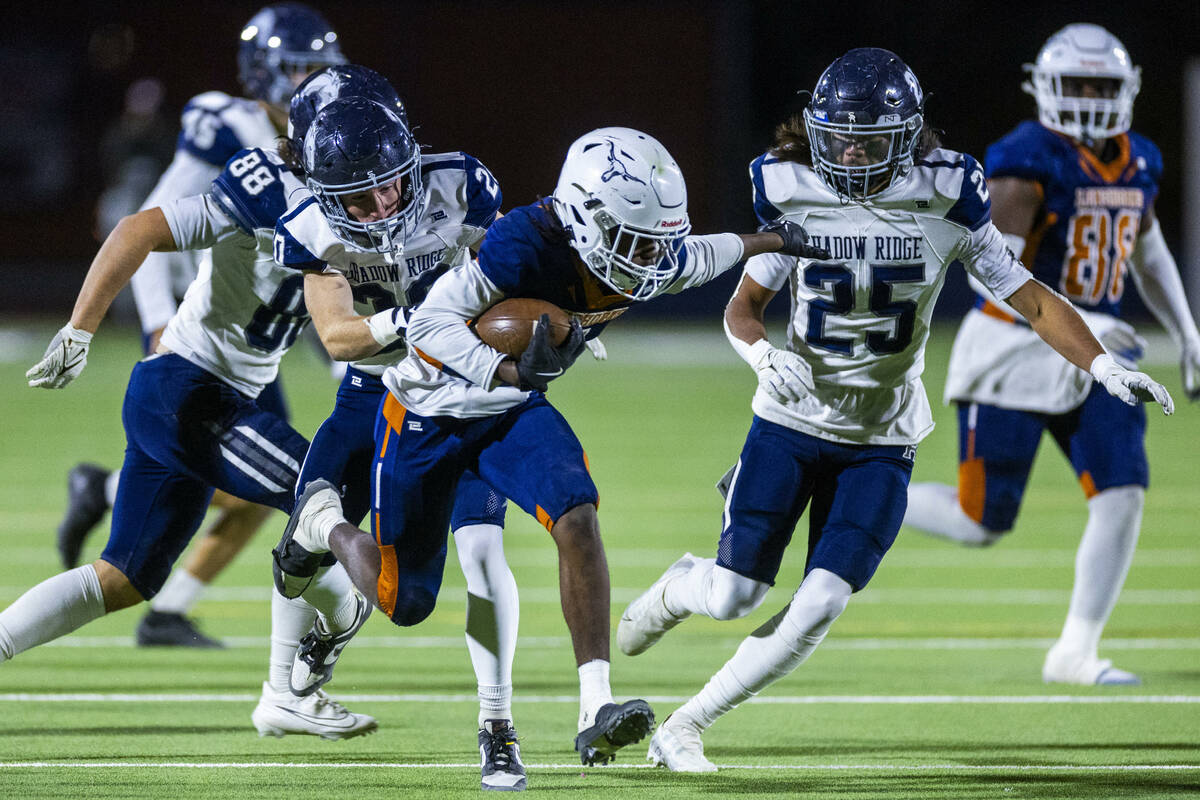 Legacy halfback Zaione Henderson (5) is grabbed from behind by Shadow Ridge safety Hawkin Ledin ...