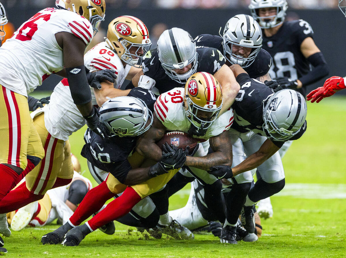 San Francisco 49ers running back Ke'Shawn Vaughn (30) is gang tackled by the Raiders defense du ...