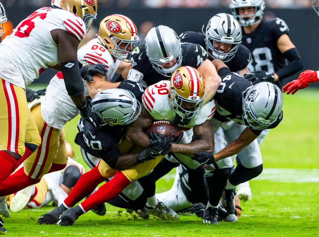 San Francisco 49ers running back Ke'Shawn Vaughn (30) is gang tackled by the Raiders defense du ...