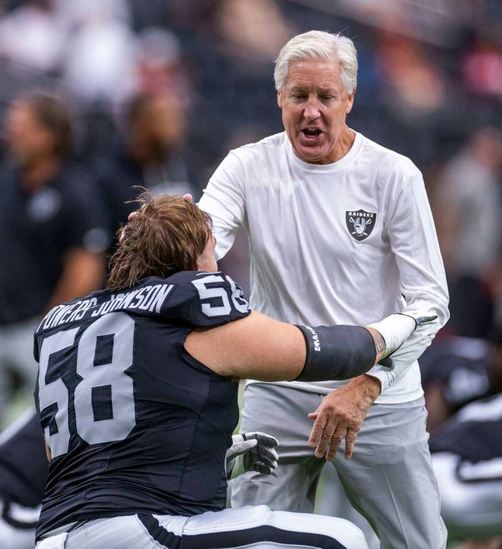Raiders head coach Pete Carroll plays around with guard Jackson Powers-Johnson (58) during warm ...