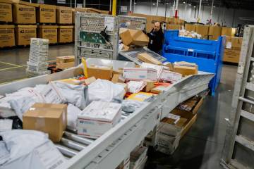 Marcos Guerra, a USPS employee, sorts packages at a distribution center in Henderson in this Re ...