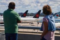 Travelers look out over grounded Air Canada planes as flight attendants picket at Pearson Inter ...