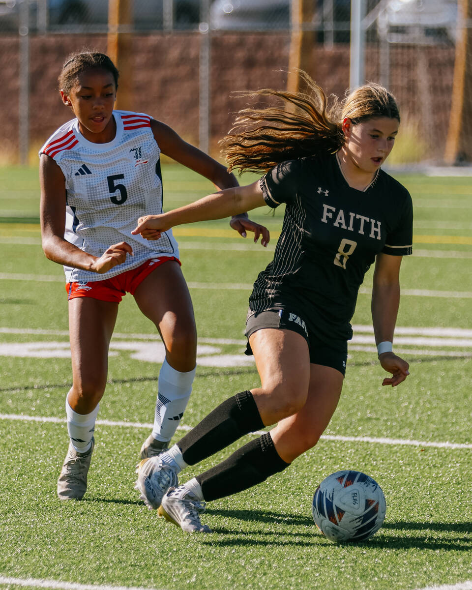 Faith Lutheran forward Olivia Stark (8) tries to keep the ball away from Liberty midfielder Mic ...