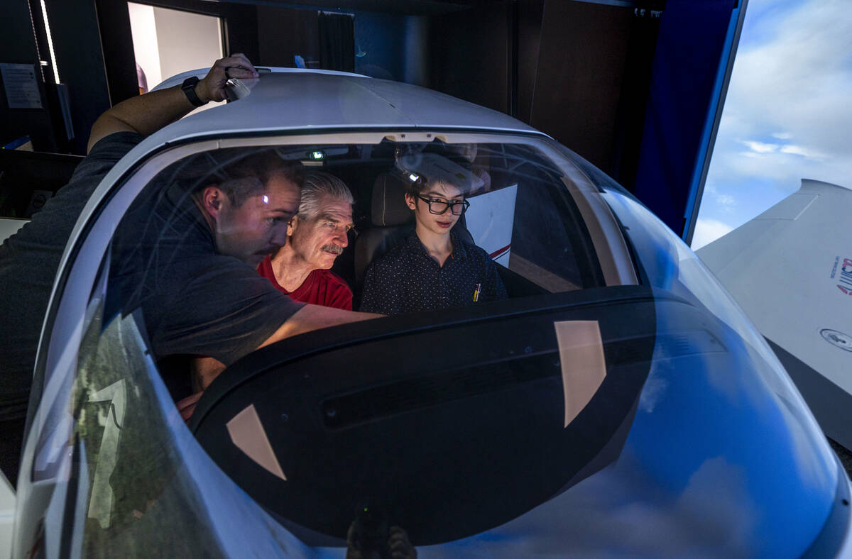 Flight instructor Phil Starcher, left, works with Mark Christensen with his son Mark who pilots ...