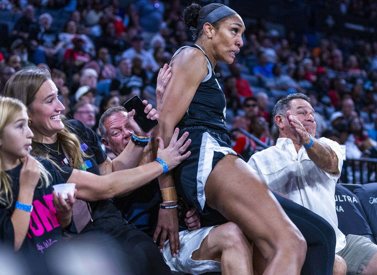 Aces center A'ja Wilson (22) lands on fans after saving a ball against the Atlanta Dream guard ...