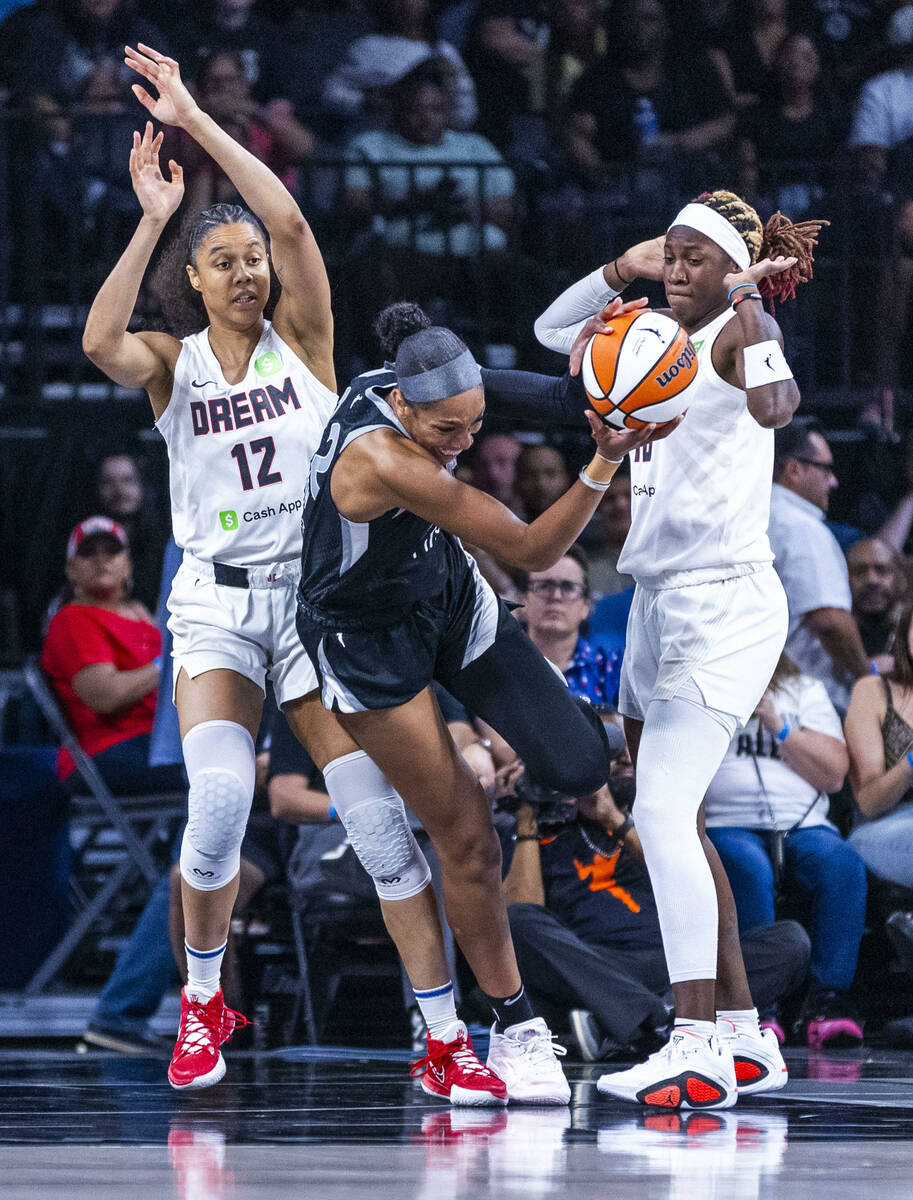 Aces center A'ja Wilson (22) is fouled after grabbing a rebound between Atlanta Dream forward N ...