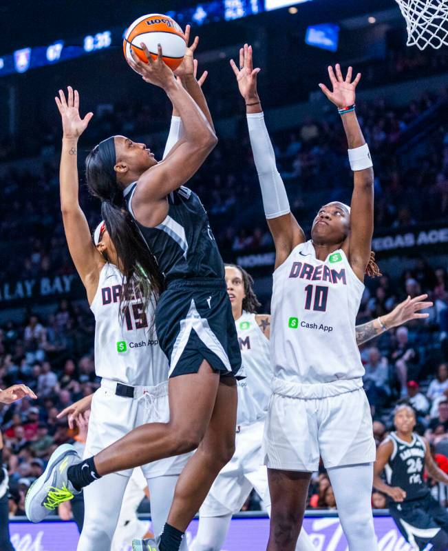 Aces guard Jackie Young (0) splits the defense of Atlanta Dream guard Allisha Gray (15) and gua ...