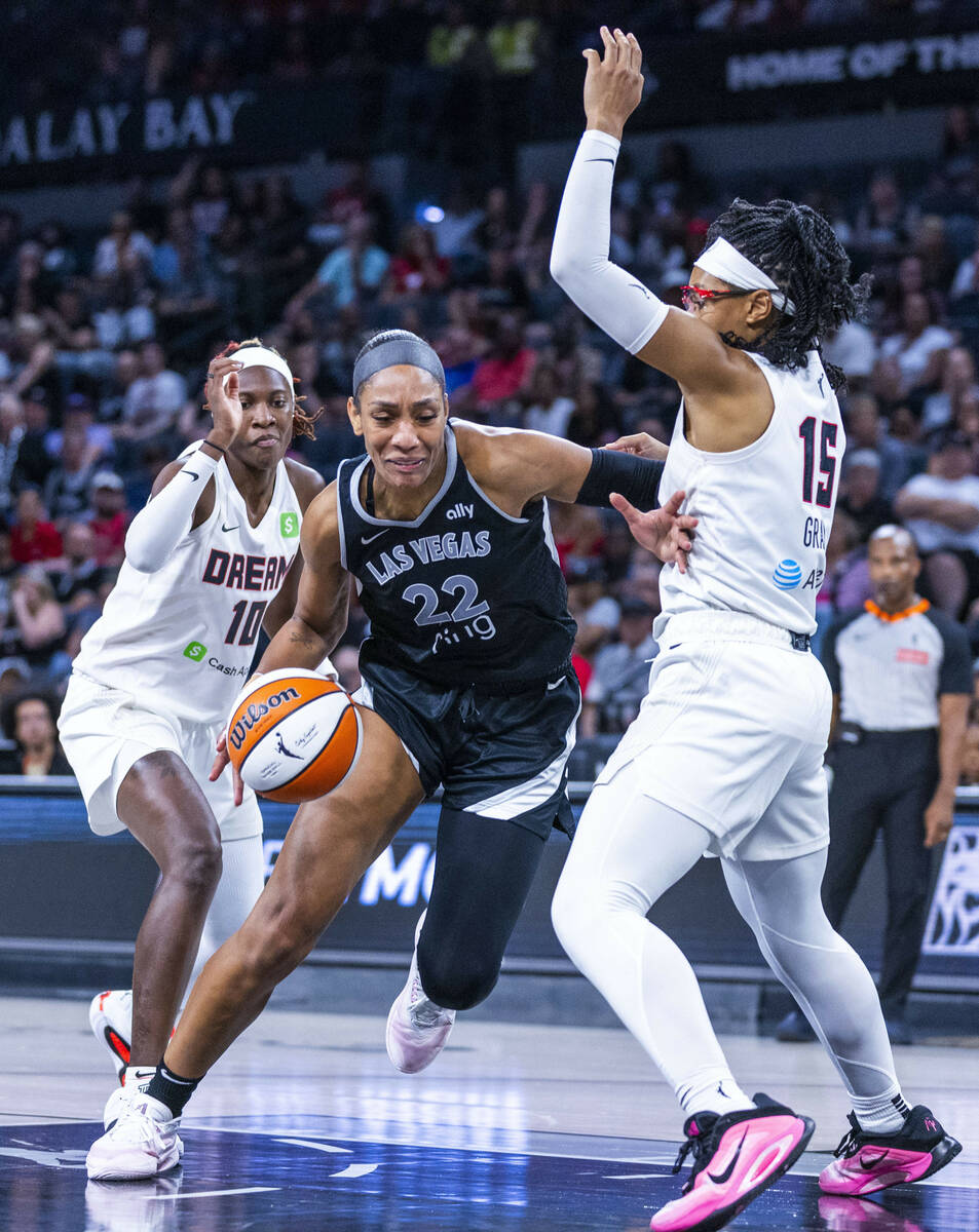 Aces center A'ja Wilson (22) splits the defense of Atlanta Dream guard Rhyne Howard (10) and gu ...